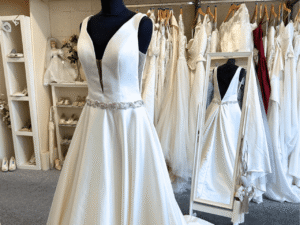 a wedding dress on a mannequin with the back of the dress visible in a mirror