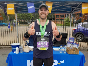 a man stands wearing a dark blue running vest
