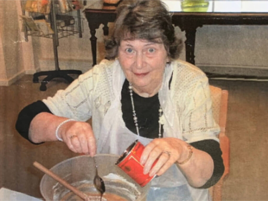 a lady sits in a chair holding a wooden spoon and makes a cake mix