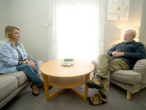 a man and a lady sit opposite each other in chairs