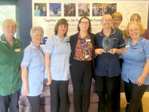 a group of people some wearing nurse scrubs hold an award trophy