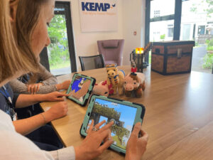 a group of people sit at a table with tablets playing the game minecraft