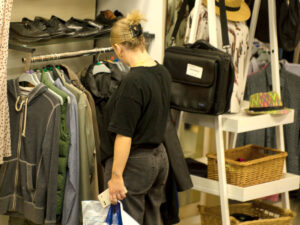 a lady looks through clothes on a rail in a charity shop
