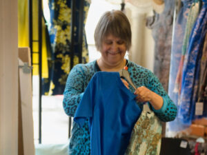 a lady stand holding clothes putting them on a hanger in a shop