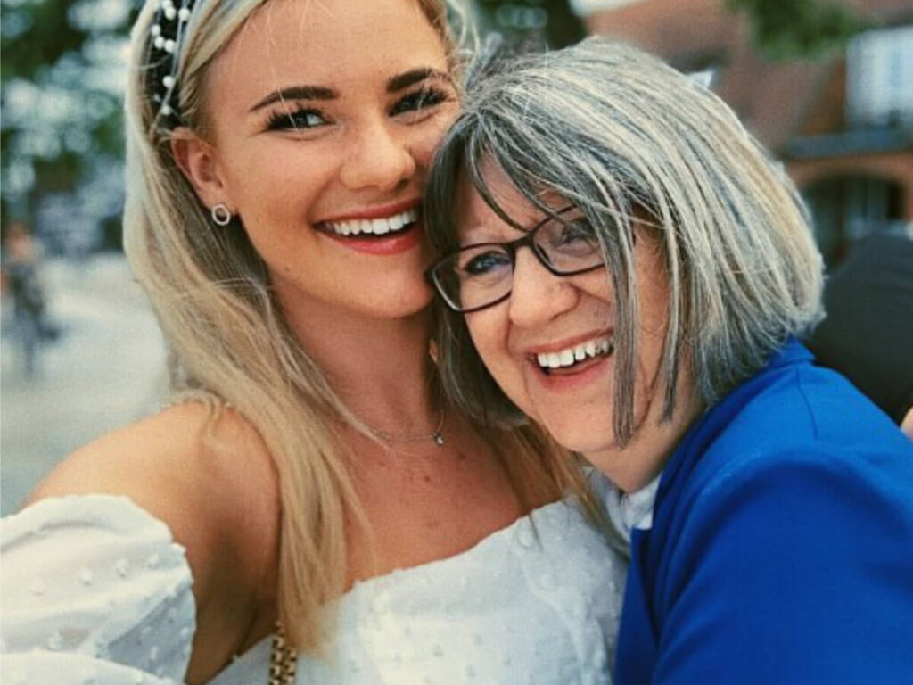 a lady stand hugging another lady in a blue jacket