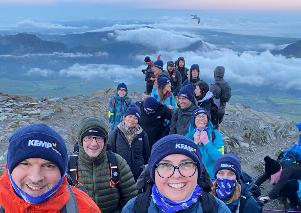 a group of people stood on top of mount snowdon at sunrise