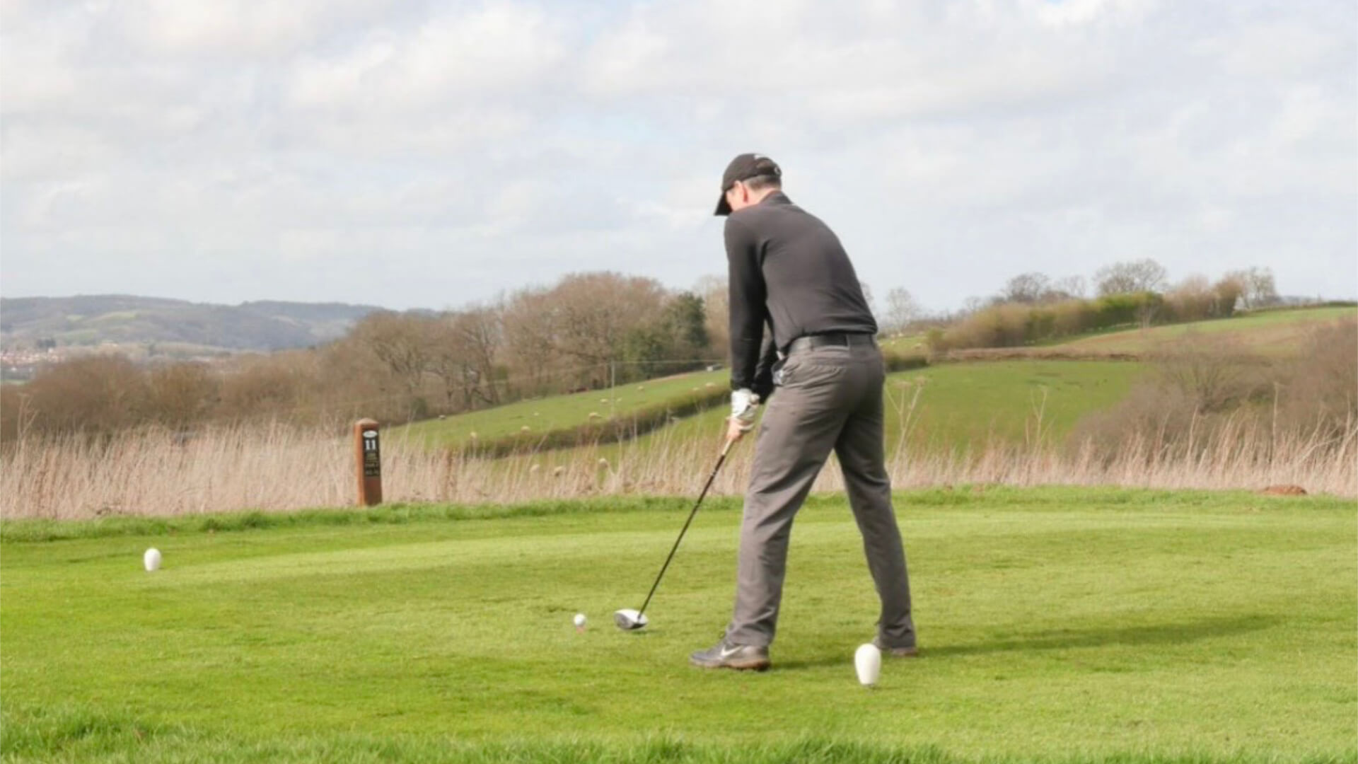 a person stands on a golf course getting ready to take a swing at the golf ball