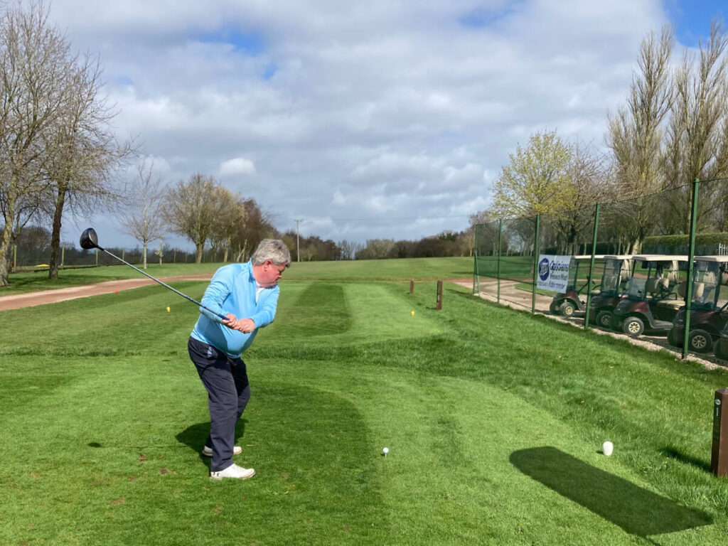 a person stands on a golf course teeing off