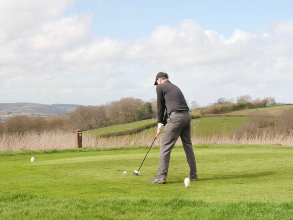 a person stands on a golf course getting ready to take a swing at the golf ball