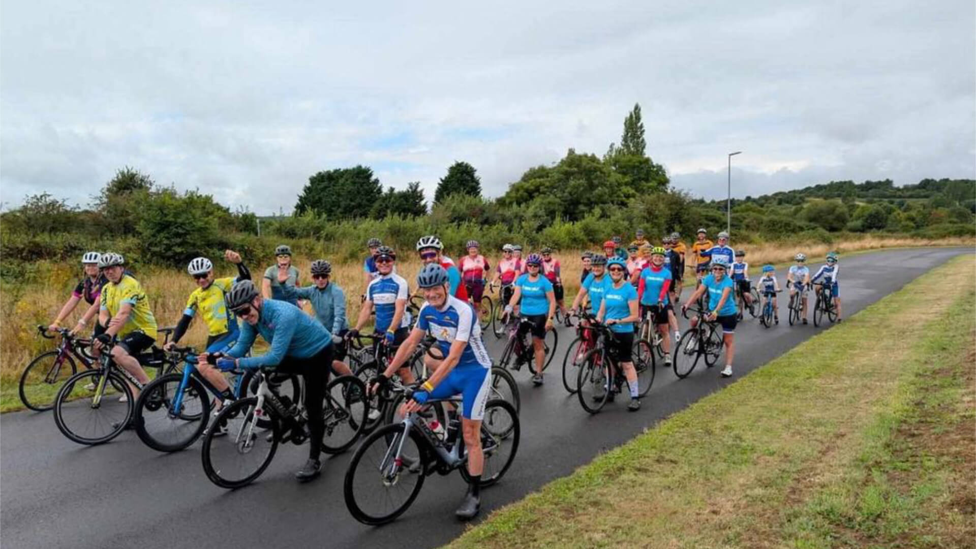a group of cyclists sit on their bikes on a road ready to cycle