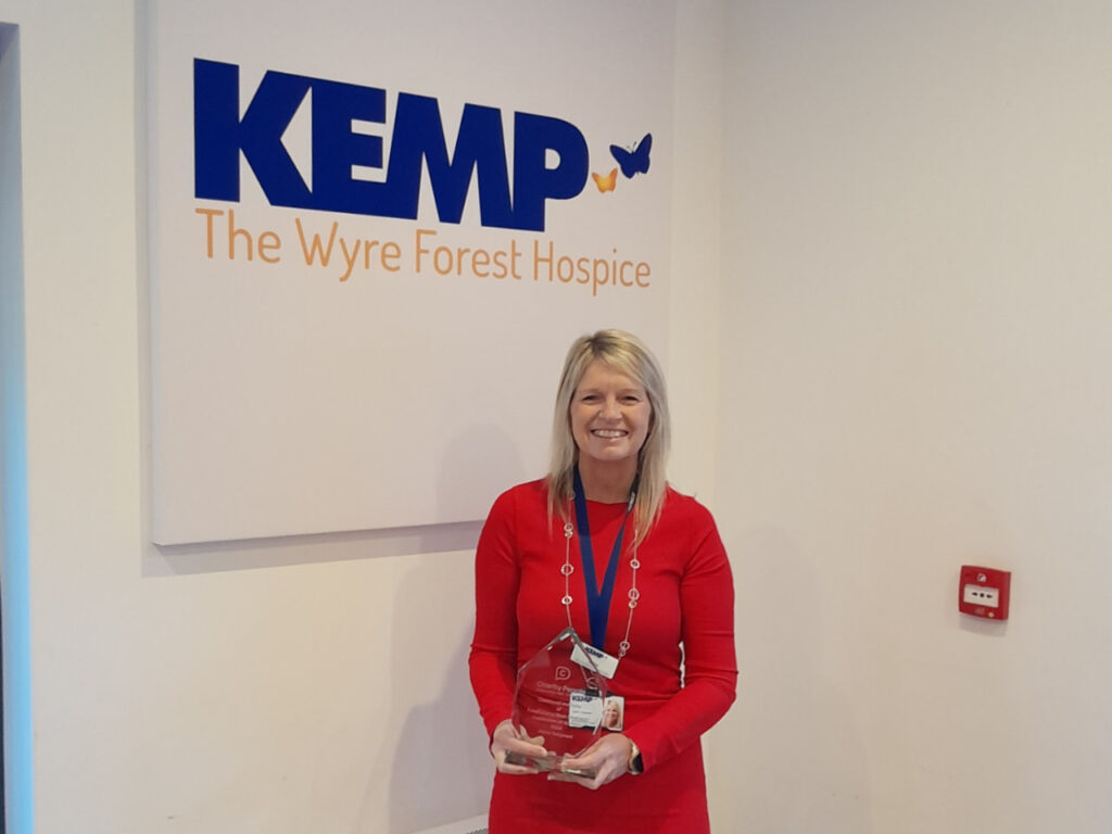 a lady in a red dress stands holding an award trophy