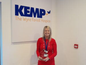 a lady in a red dress stands holding an award trophy