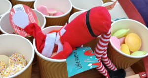 a elf on the shelf scout elf is face down in a cup of sweets