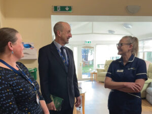 a hospice nurse in uniform stands to the right as she talks to two other people