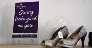 a photo of silver shoes sat on a shelf top next to a purple sign