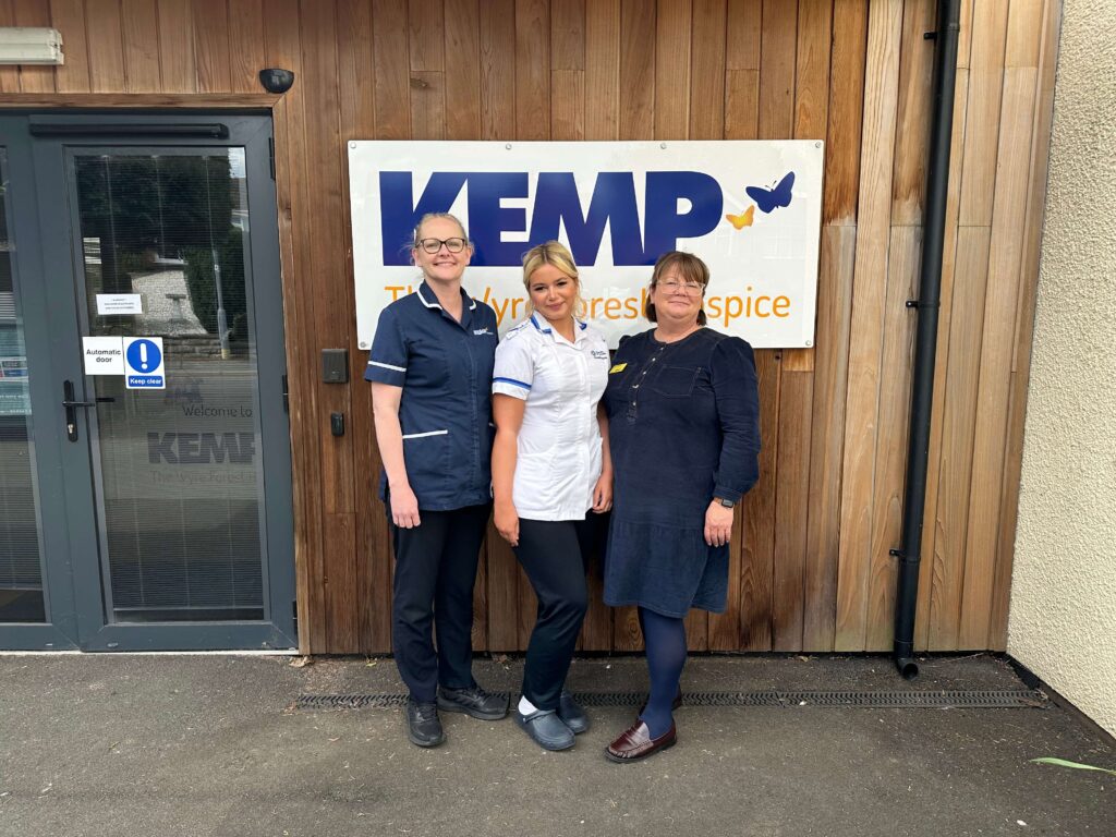 three nurses stood in front of the KEMP Hospice sign