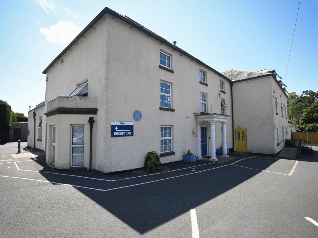 the exterior of a cream building on a sunny day with a clear blue sky. the building has multiple windows to the front of the building.