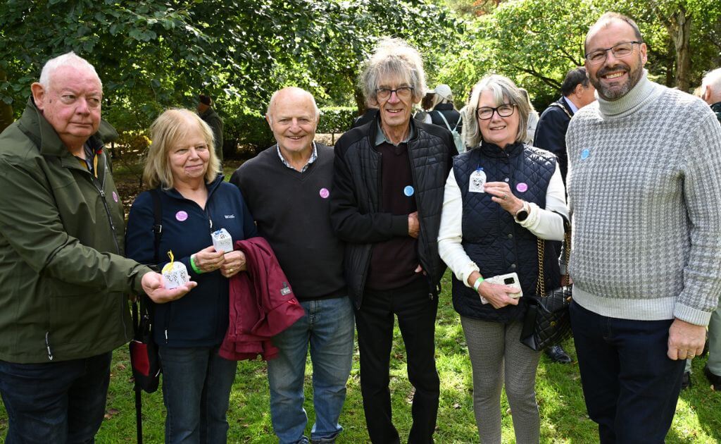 a group of people stand in a wooded area