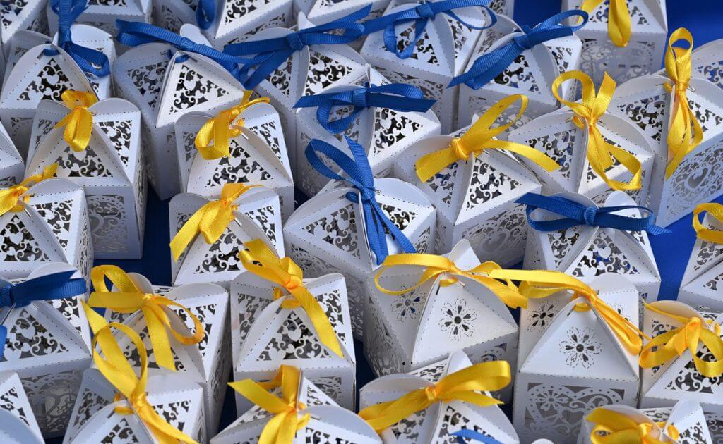 close up of decorative white boxes with a variety of blue and yellow ribbon bows tied on the top