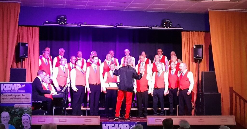 a male choir stand on a stage singing at a concert
