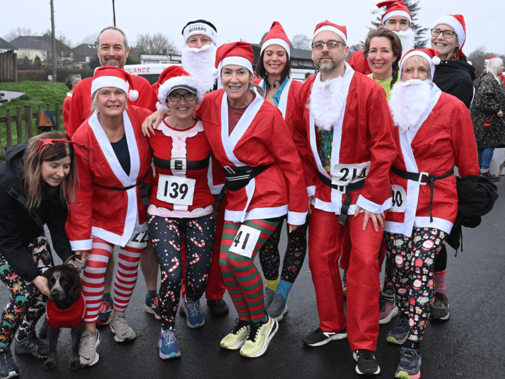 a group of people stand together wearing santa suits at the kemp santa fun run