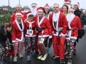a group of people stand together wearing santa suits at the kemp santa fun run