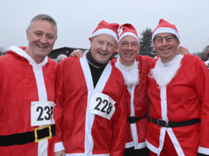 four men stand together in santa suits at the kemp santa fun run