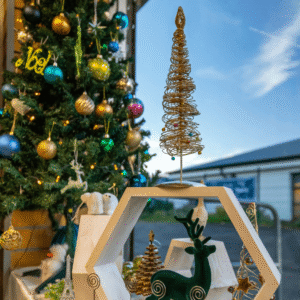 inside a shop window with a decorated christmas tree and a disaply of christmas items. Looking out to a blue sky outside the shop.