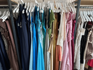 A selection of colourful dresses hang on a shops clothes rail