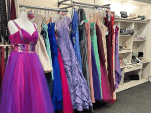 A selection of colourful dresses hang on a shops clothes rail
