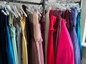 A selection of colourful dresses hang on a shops clothes rail