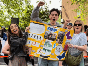 three people hold a banner and cheer for runners at London marathon