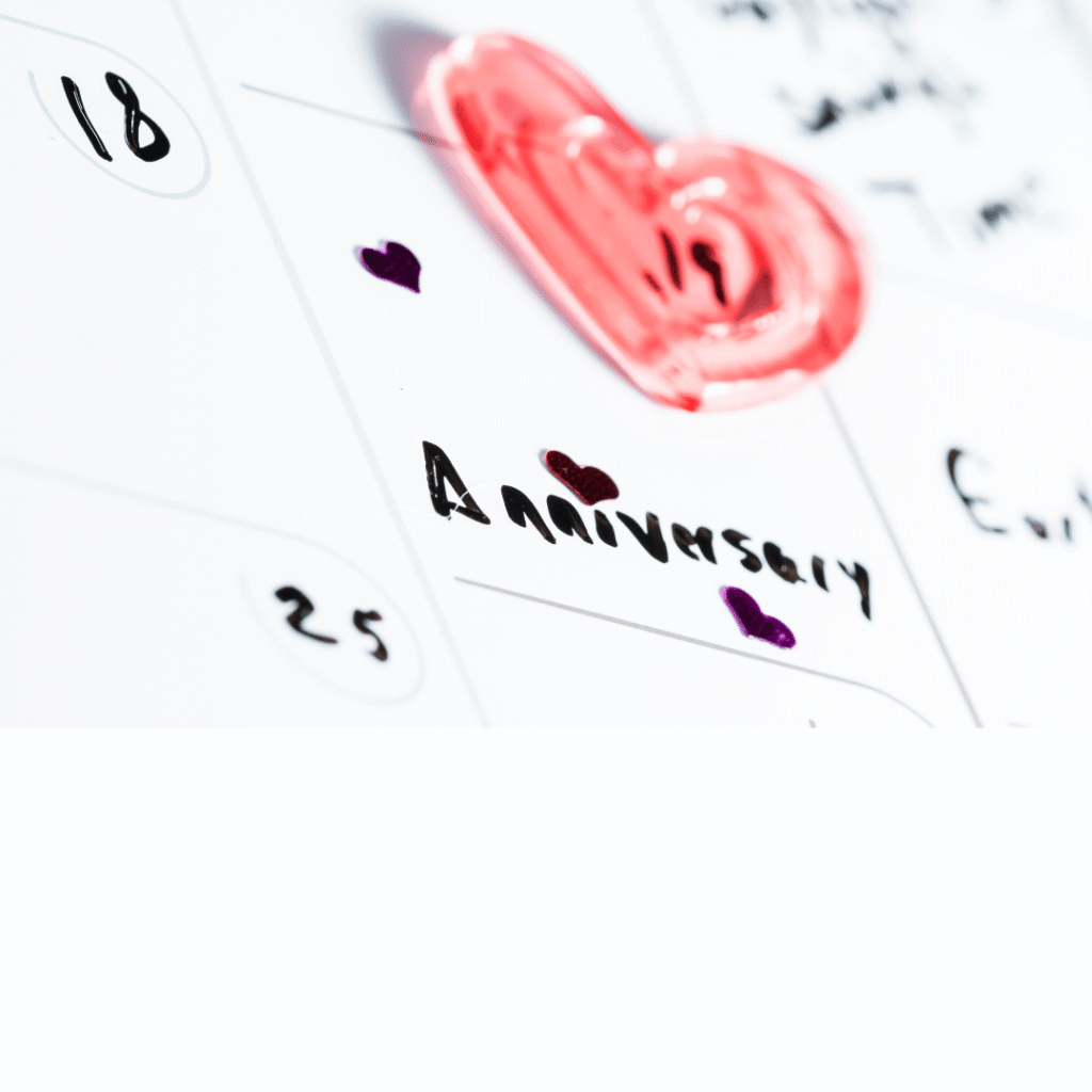 a heart magnet sits on a white board saying the word anniversary