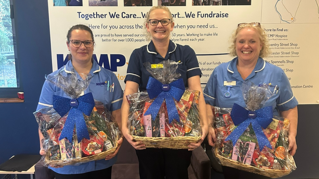 Three, nurses stood smiling holding a christmas hamper