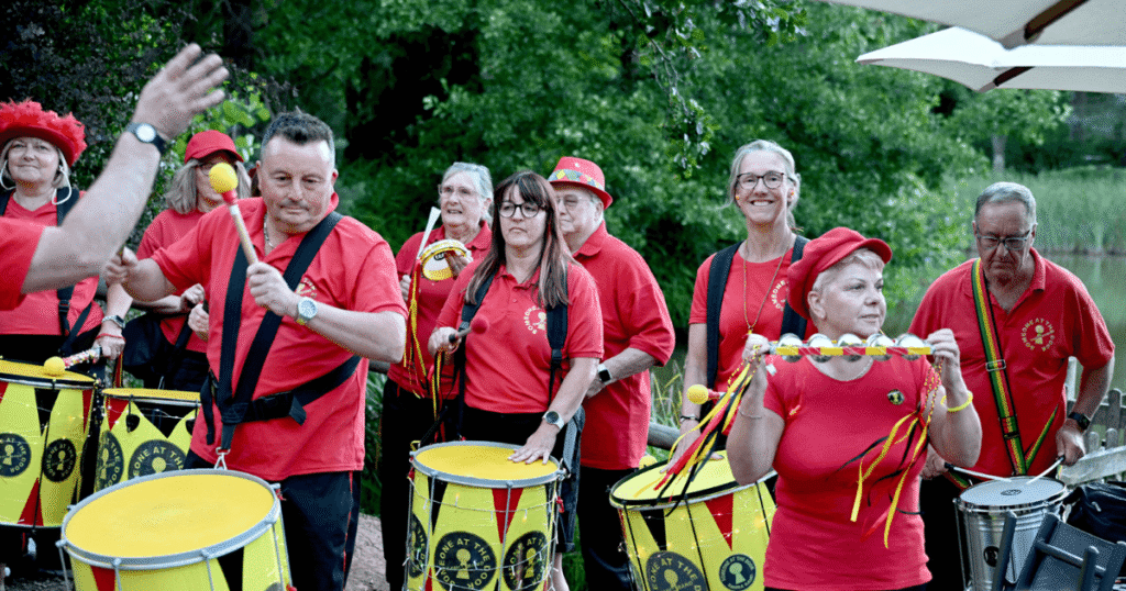 a samba band planning. They are wearing red t shirts and have bright yellow drums