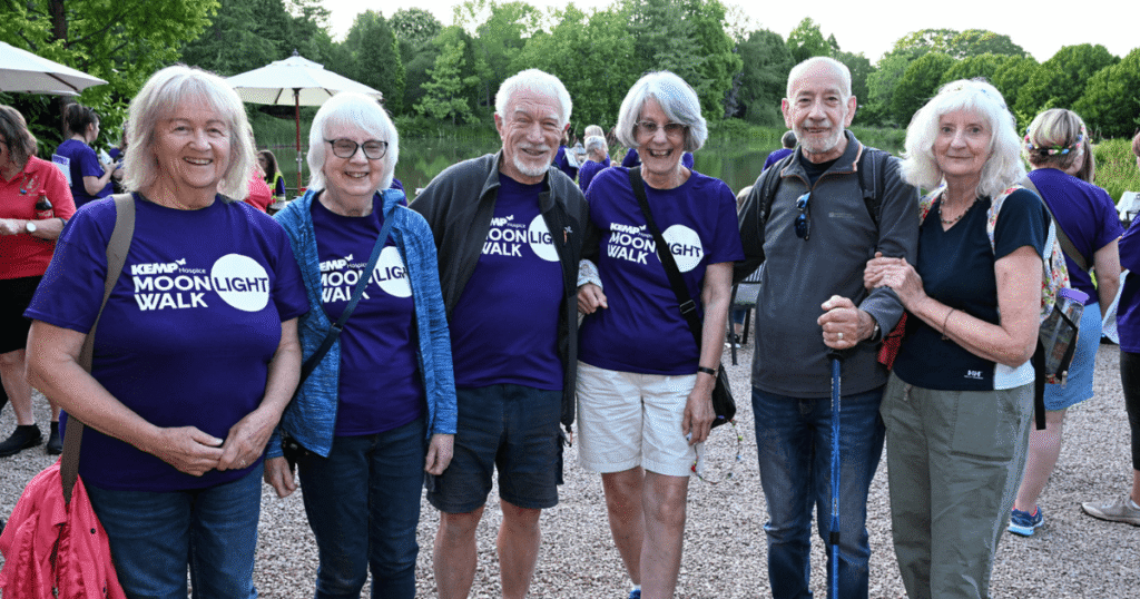 a group stand together with a lake in the background, some wearing kemp moonlight walk t shirts