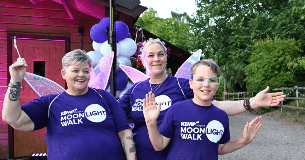 three people stand together wearing purple kemp moonlight walk t shirts and two wearing glittery fairy wings