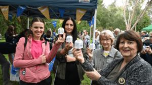 A group of people stand together holding decorative white boxes containing a butterfly