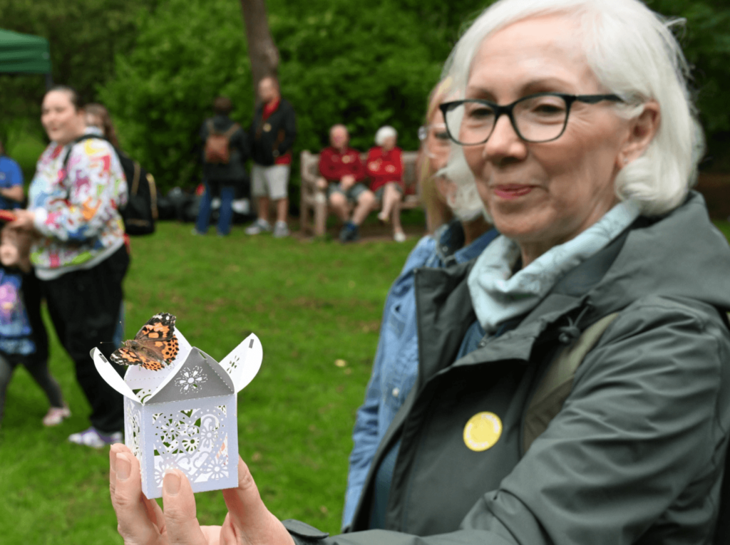 a lady holds a white box with a butterfly sat on the opening of the box.
